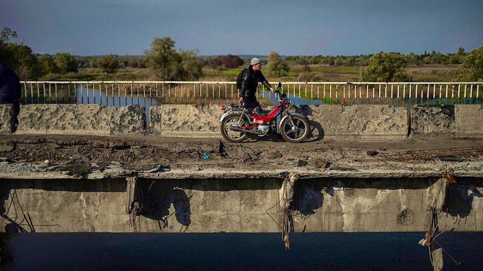 ARCHIVE - A man pulls his motorcycle on a destroyed bridge over the Oskil River (archive photo). Photo: Evgeniy Maloletka/AP/dpa