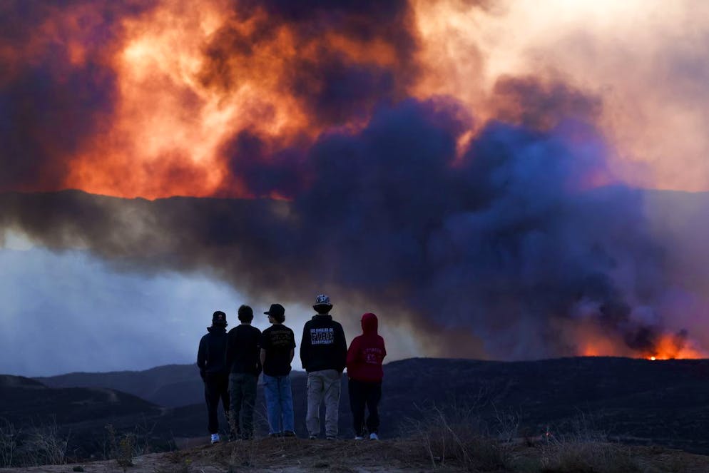 Des personnes observent les activités de lutte contre les incendies sur une section de l'incendie de forêt Hughes près de Santa Clarita, Californie, États-Unis, 22 janvier 2025. L'incendie Hughes s'est déclaré aujourd'hui au nord de Los Angeles, où de nombreux feux de forêt ont déjà détruit des milliers d'habitations et forcé des milliers de personnes à évacuer de nombreux quartiers au cours des dernières semaines.
