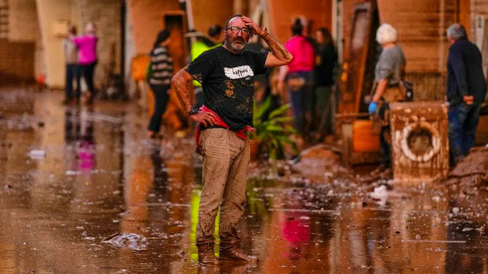 A man stands in despair in a street affected by the floods in Valencia.