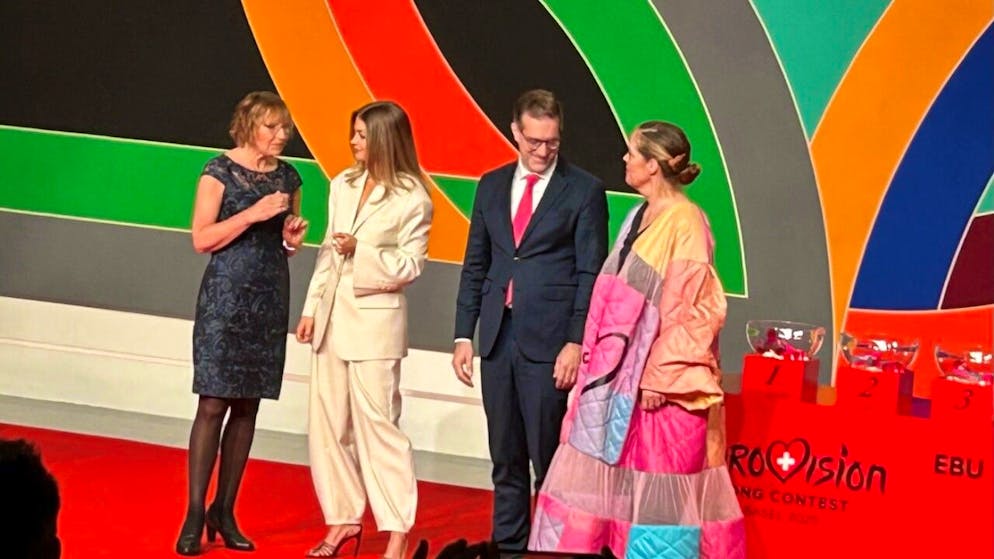 La presidente del parlamento di Malmö Carina Nilsson (sinistra) passa il testimone dell'ESC al presidente del governo basilese Conradin Cramer. Al centro la moderatrice Jennifer Bosshard.