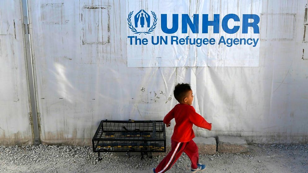 ARCHIV - Ein kleiner Junge läuft an einem UNHCR-Logo vorbei. Foto: Michael Varaklas/AP/dpa