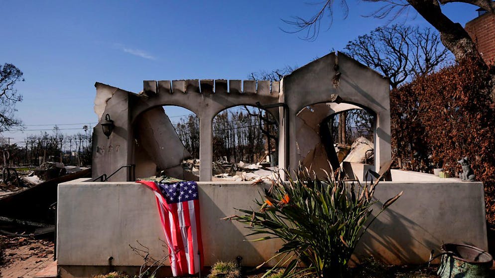 ARCHIV - Eine US-Flagge ist vor einem vom Feuer verwüsteten Grundstück in der Brandzone des Palisades-Feuers im Stadtteil Pacific Palisades von Los Angeles drapiert. Foto: Jae C. Hong/AP/dpa/Archivbild