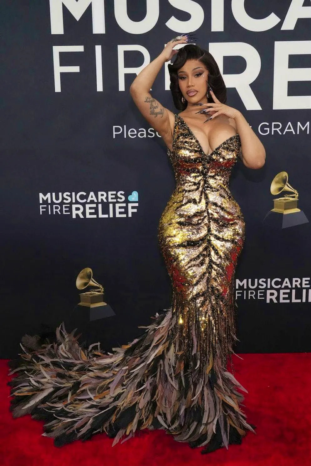 Grammy Awards 2025 - Tapis rouge. On reconnaît la signature de Roberto Cavalli: Cardi B se transforme en chat sauvage arborant une robe dorée à paillettes de la maison de couture italienne, style accentué par les griffes et les yeux maquillés façon cateye.
