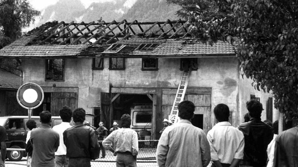 Alcuni richiedenti l'asilo tamil di fronte al centro d'accoglienza di Coira distrutto dalle fiamme nel luglio 1989. (immagine d'archivio)