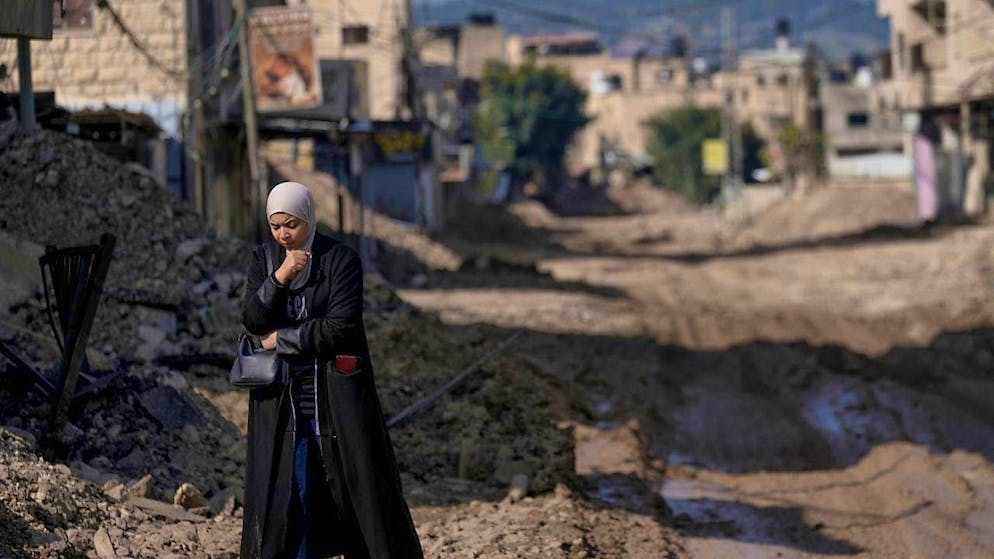 A Palestinian woman walks along a destroyed street in the Jenin refugee camp. Photo: Majdi Mohammed/AP/dpa