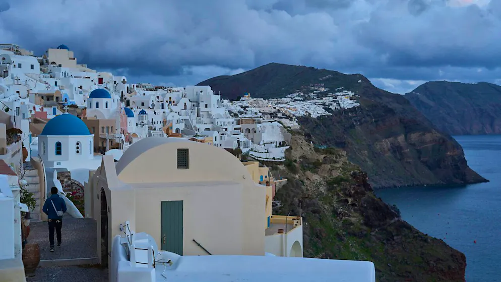 Ein Tourist nähert sich einer orthodoxen Kirche mit blauer Kuppel in Oia auf der erdbebengeschädigten Insel Santorini. Derzeit bebt die Erde auf der Insel fast im Zehn-Minuten-Takt. Das betreffende Beben erreichte mit Stärke 5 einen vorläufigen Höchstwert. Foto: Petros Giannakouris/AP/dpa
