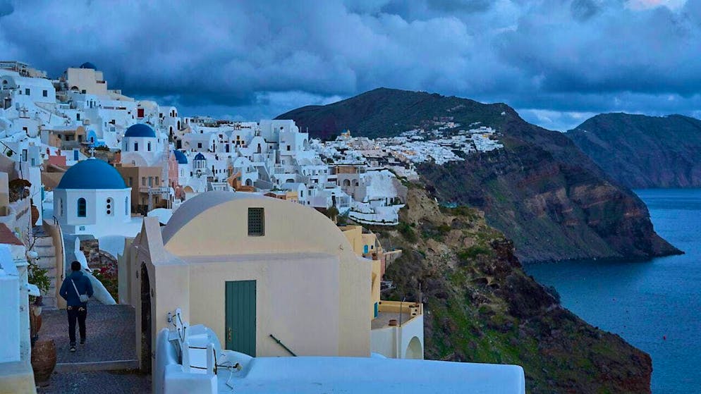 A tourist approaches an orthodox church with a blue dome in Oia on the earthquake-stricken island of Santorini. The earth is currently shaking on the island almost every ten minutes. The quake in question reached a temporary peak of magnitude 5. Photo: Petros Giannakouris/AP/dpa