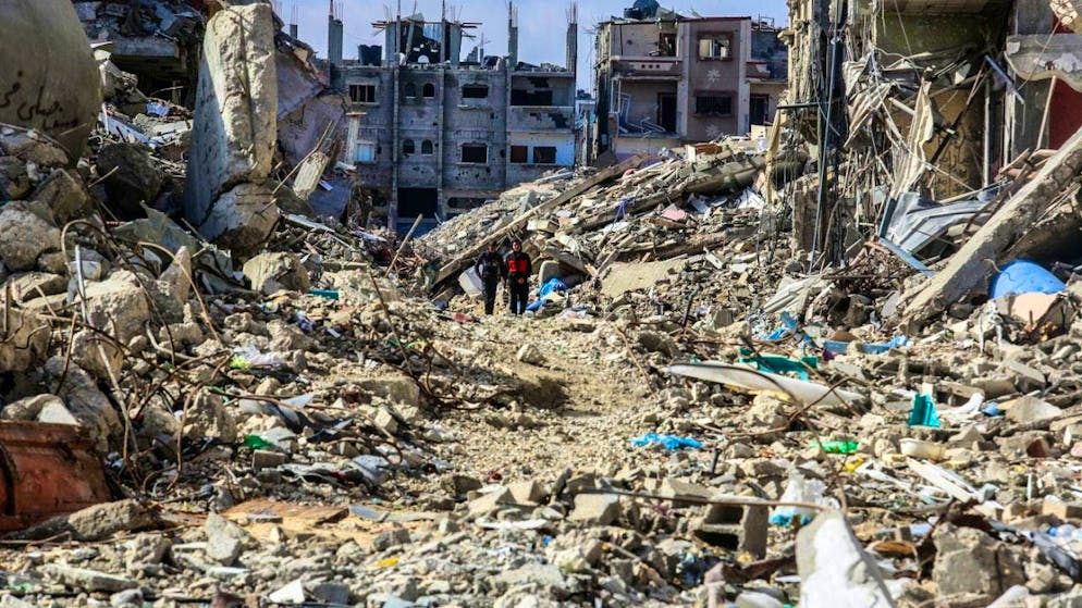 ARCHIVE - Palestinians walk past destroyed houses, a few days after the ceasefire between Israel and Hamas came into force. Photo: Abed Rahim Khatib/dpa