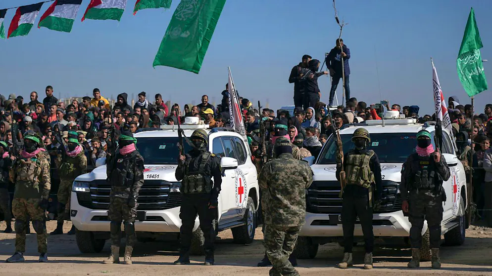 Kämpfer der Hamas und des Islamischen Dschihad beziehen Stellung vor Autos des Internationalen Roten Kreuzes, die auf die israelischen Geiseln Iair Horn, Alexander (Sascha) Trufanov und Sagui Dekel Chen warten, die seit dem 7. Oktober 2023 in Gaza als Geiseln gehalten werden. Foto: Abdel Kareem Hana/AP/dpa