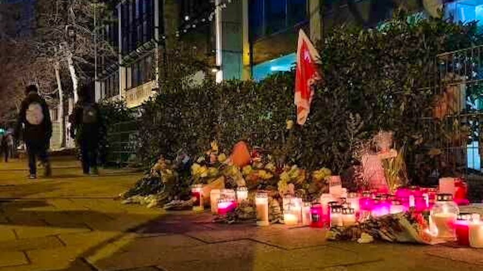 Flowers and candles stand on the sidewalk near the spot where a car drove into a group of protesters on February 13, 2025.