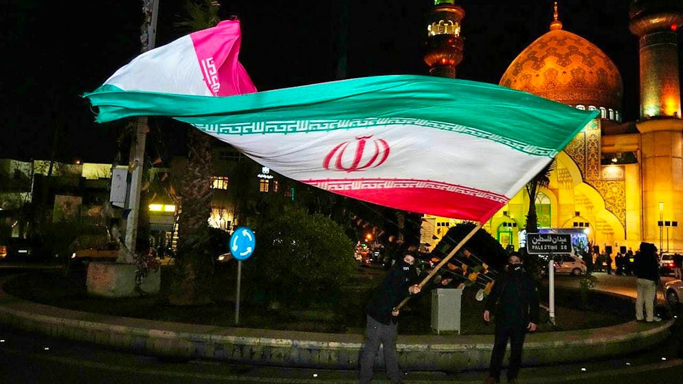 ARCHIVE - A demonstrator waves an Iranian flag during a ceremony to mark the announcement of a ceasefire between Hamas and Israel at Felestin (Palestine) Square in Tehran. Photo: Vahid Salemi/AP/dpa