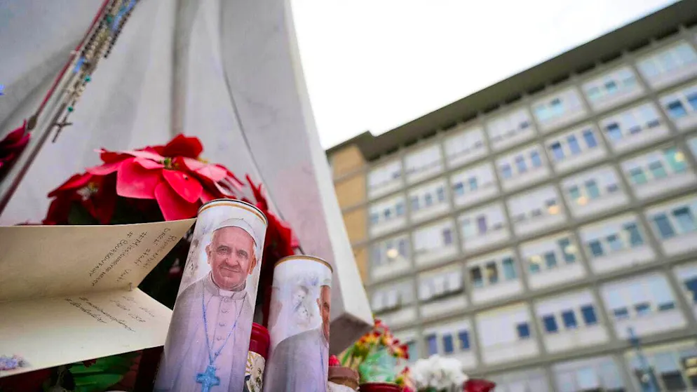 Candles with the image of Pope Francis are placed under the statue of the late Pope John Paul II in front of the Agostino Gemelli Polyclinic in Rome, where the Pope has been treated since Friday, February 14, 2025. Photo: Gregorio Borgia/AP/dpa