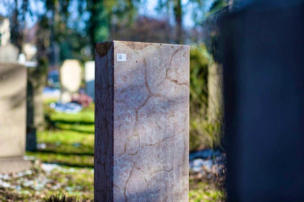 A QR code can be seen on the back of a gravestone. Hard-to-remove stickers that lead to digital data about the grave have appeared on around 1000 graves in Munich. The police are investigating.