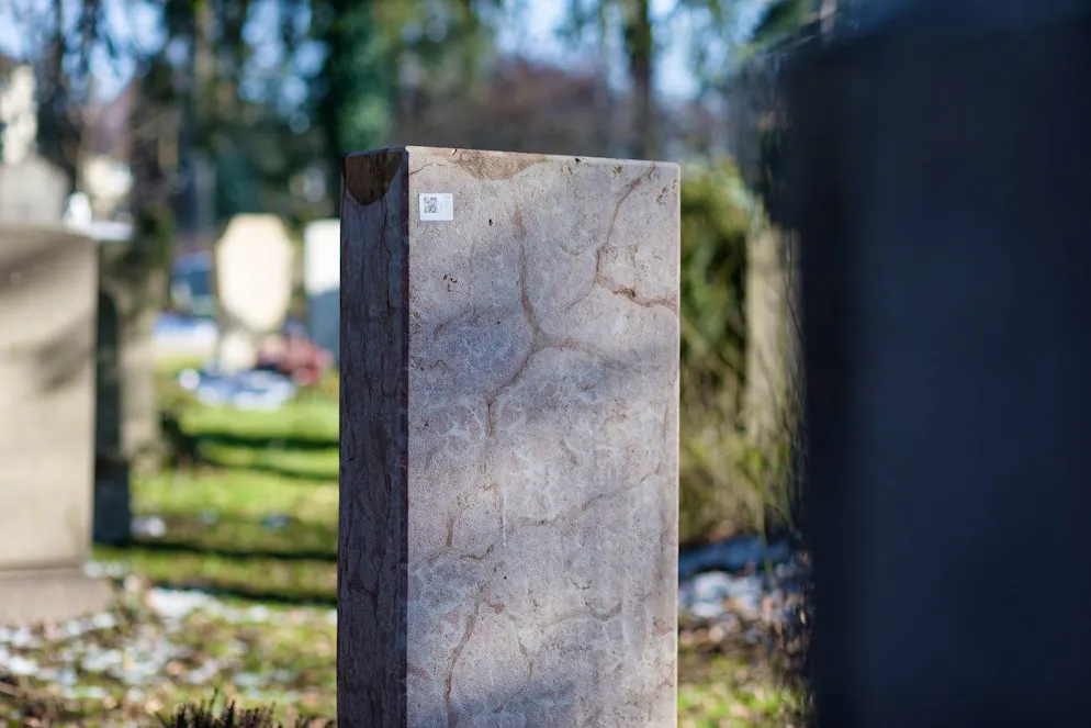 Ein QR-Code ist an der Rückseite eines Grabsteines zu sehen. An etwa 1000 Gräbern in München tauchten schwer abzulösende Aufkleber auf, die zu digitalen Daten über das Grab führen. Die Polizei ermittelt. 