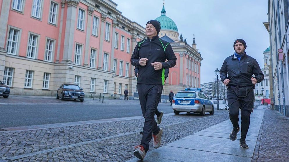 Bundeskanzler Olaf Scholz (SPD, l.) joggt in Begleitung von seinem Personenschutz am Sonntagmorgen.