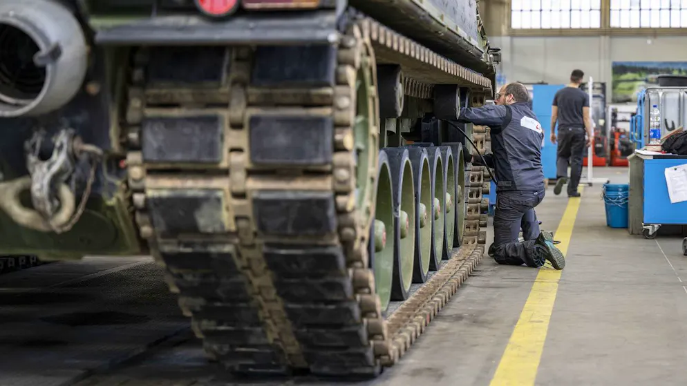 Ein Mechaniker wartet die Raupen an einem Leopard-2-Panzer in einer Halle der Ruag in Thun.
