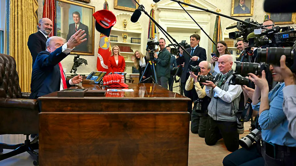 US-Präsident Donald Trump wirft eine Kappe mit der Aufschrift «Trump Was Right About Everything» während er mit Reportern spricht, im Oval Office des Weißen Hauses. Foto: Uncredited/Pool/AP/dpa