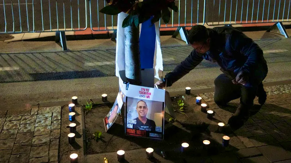 A man lights candles and shows photos of four dead Israeli hostages, who according to Hamas were handed over to Israel, in front of the Abu Kabir Forensic Institute while waiting for their arrival and identification. Photo: Mahmoud Illean/AP/dpa