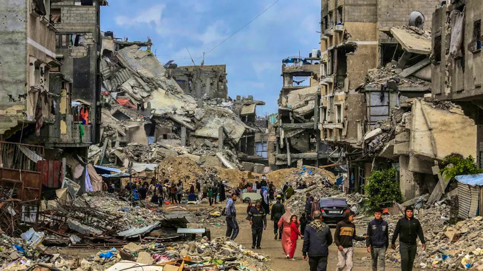 ARCHIVE - Palestinians walk between destroyed buildings in Chan Junis. Photo: Abed Rahim Khatib/dpa