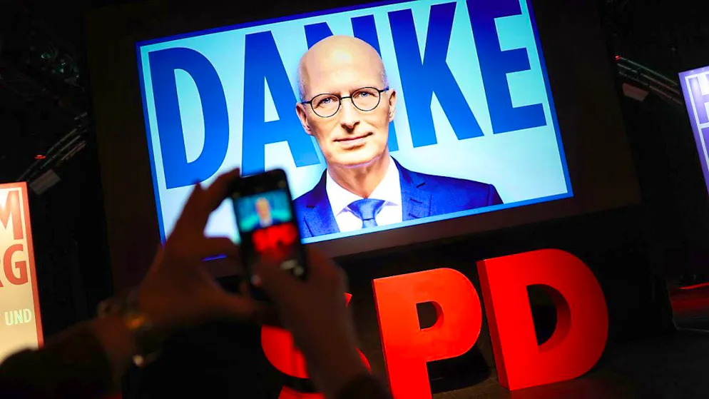 A person uses a smartphone to photograph a video wall with the words "Thank you" and the face of Peter Tschentscher (SPD), First Mayor of Hamburg, at the Hamburg SPD election party in the Markthalle. A new parliament was elected in Hamburg on Sunday. Photo: Christian Charisius/dpa