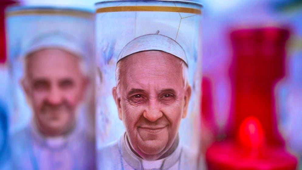 ARCHIVE - Candles with photos of Pope Francis. Photo: Alessandra Tarantino/AP/dpa