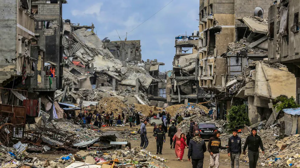 ARCHIV - Palästinenser gehen durch die zerstörten Gebäude, nachdem sich die israelischen Streitkräfte im Rahmen der Waffenruhe mit der Hamas zurückgezogen haben. Foto: Abed Rahim Khatib/dpa