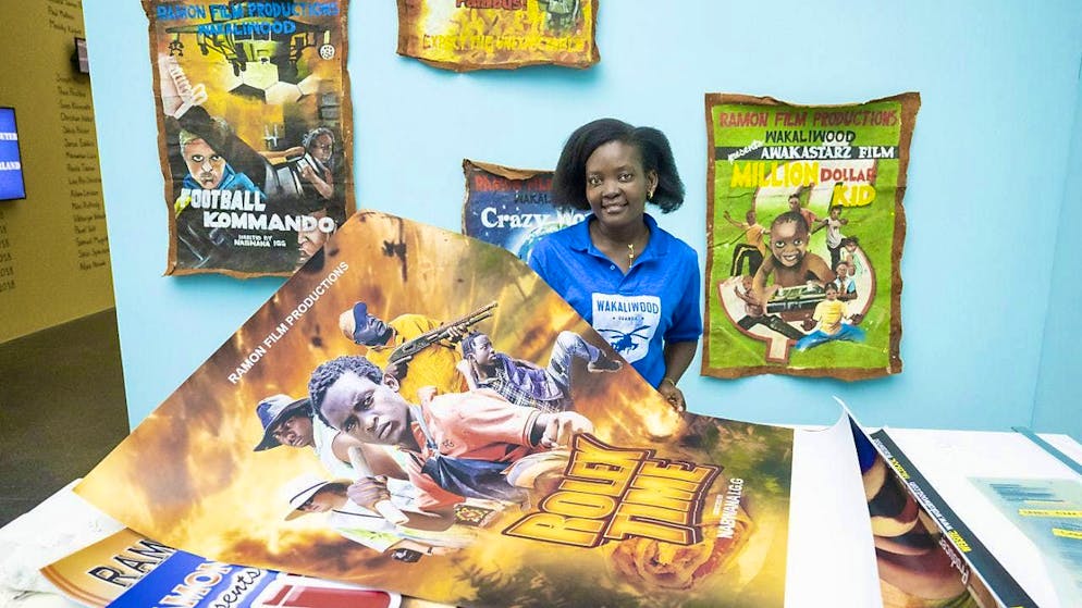 Kunstmuseum Luzern shows collages by Małgorzata Mirga-Tas - Gallery. The co-producer of Wakaliga, Harriet Nakasujja, presents the poster for the film "Rolex Time". In the background, painted posters for earlier Wakaliga films.