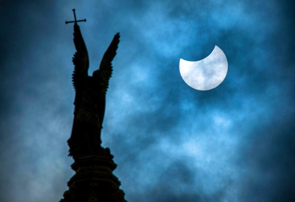 Sun, moon and stars in March - Lunar and solar eclipse - Gallery. A partial solar eclipse over the statue of the Archangel Michael on the dome of Schwerin Castle.