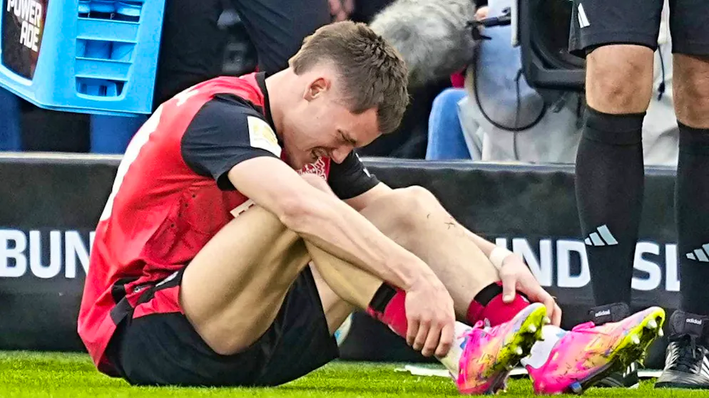 Florian Wirtz writhes in pain after a foul by Mitchell Weiser