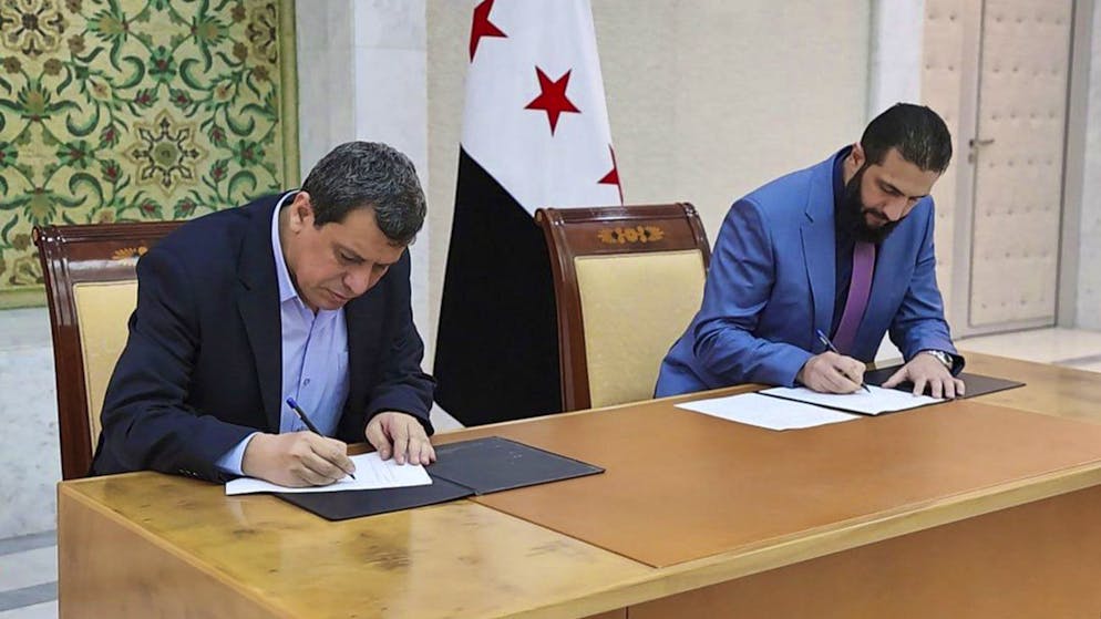 Syriens Übergangspräsident Ahmed al-Scharaa (rechts) und SDF-Oberkommandeur Maslum Abdi unterschreiben am Montag in Damaskus das Abkommen.