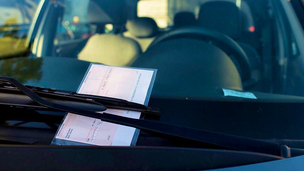 A parking fine stuck behind a windshield wiper. (symbolic image)