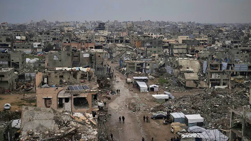 ARCHIV - Palästinenser gehen durch die Trümmer zerstörter Häuser und Gebäude in Gaza-Stadt. Foto: Jehad Alshrafi/AP/dpa