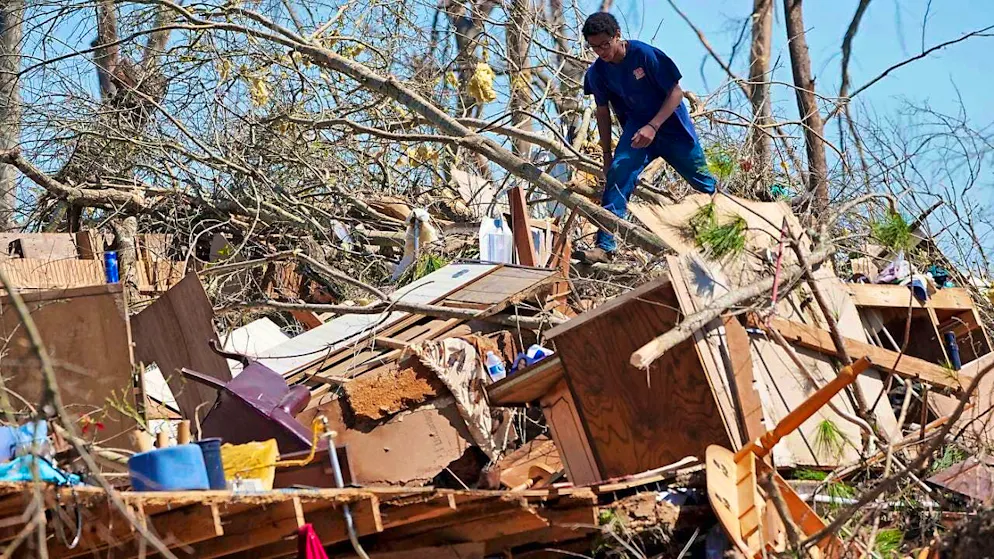 Trey Bridges climbs a mountain of debris after a tornado to help the Blansett family salvage items. Photo: Rogelio V. Solis/AP/dpa
