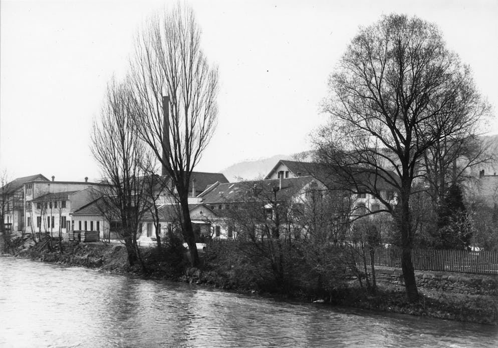 Papierfabrik an der Sihl: Die Werke Giesshübel und Manegg. Die Papierfabrik von der Lessingstrasse vom anderen Sihlufer aus gesehen. «Bilanz» schreibt: «Nach dem Motto ‹Was wir nicht posten, postet die Konkurrenz› sackte [der CEO] reihenweise Firmen ein, bis die Produktionspalette sich in einzigartiger Unüberschaubarkeit präsentierte.»