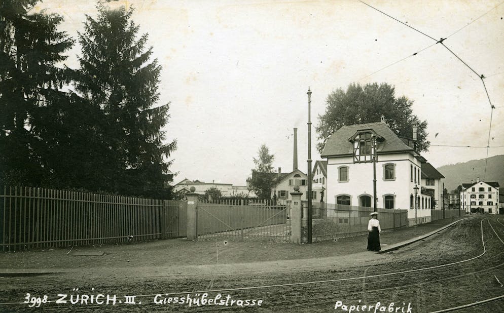 Papierfabrik an der Sihl: Die Werke Giesshübel und Manegg. Die Papyrus Schweiz AG ist im Papier-Grosshandel tätig, gehört der schwedischen Finanzinvestmentgesellschaft Altor und <a target="_blank" rel="nofollow" href="https://www.papyrus.com/deCH/papyrus-history">beruft sich</a> auf seine schwedische Geschichte.<br>Im Bild: Die Giesshübelstrasse circa 1908 mit der Papierfabrik im Hintergrund. Das vordere Haus wird von der Papierfabrik an der Sihl durch einen mehrstöckigen Bau für die Arbeiterschaft ersetzt, das heute noch steht.