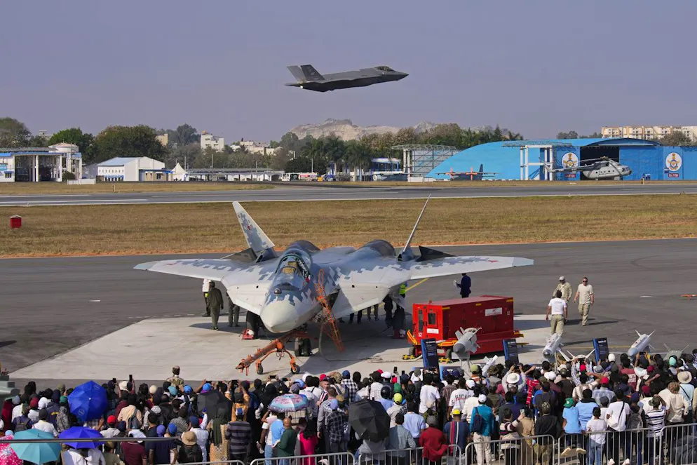 Bei einer Flugshow in Bengaluru in Indien startet am 13. Februar eine amerikanische F-35, während im Vordergrund Besuchenden eine russische Su-57 bestaunen.