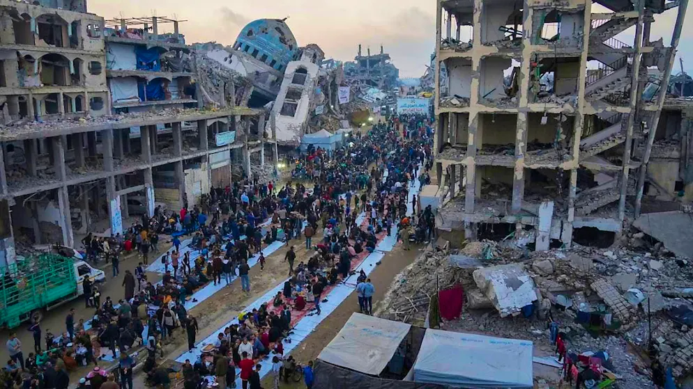 Surrounded by destroyed houses and buildings, Palestinians gather for iftar, the breaking of the fast during Ramadan, in Beit Lahia in the northern Gaza Strip. Photo: Jehad Alshrafi/AP/dpa