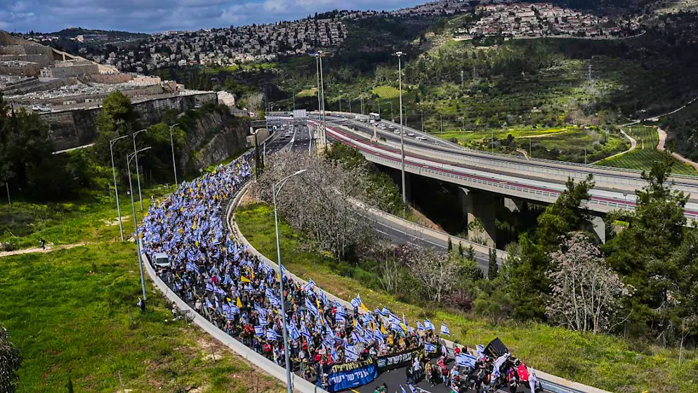 Israelis marschieren auf einer Autobahn in Richtung Jerusalem, um gegen die Pläne von Ministerpräsident Netanjahu zu protestieren, den Chef des internen Sicherheitsdienstes Bet zu entlassen. Foto: Ohad Zwigenberg/AP/dpa