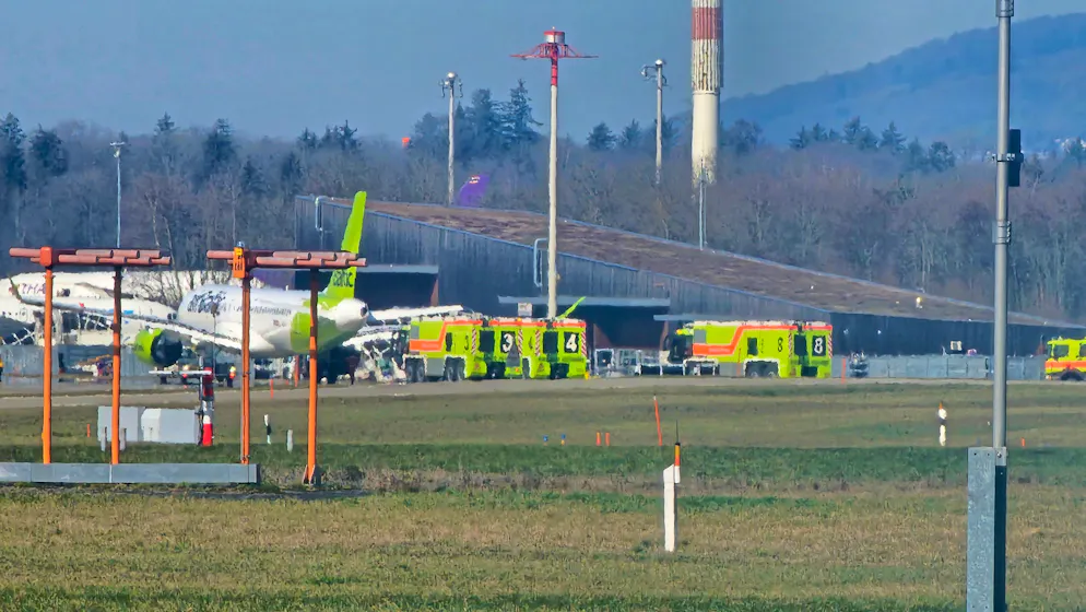 Ein Bild zeigt die Maschine umringt von Feuerwehrfahrzeugen. 