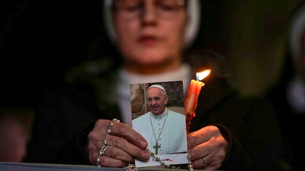 A nun holds a candle and a picture of Pope Francis during a rosary prayer for his health in St. Peter's Square at the Vatican. Photo: Andrew Medichini/AP/dpa