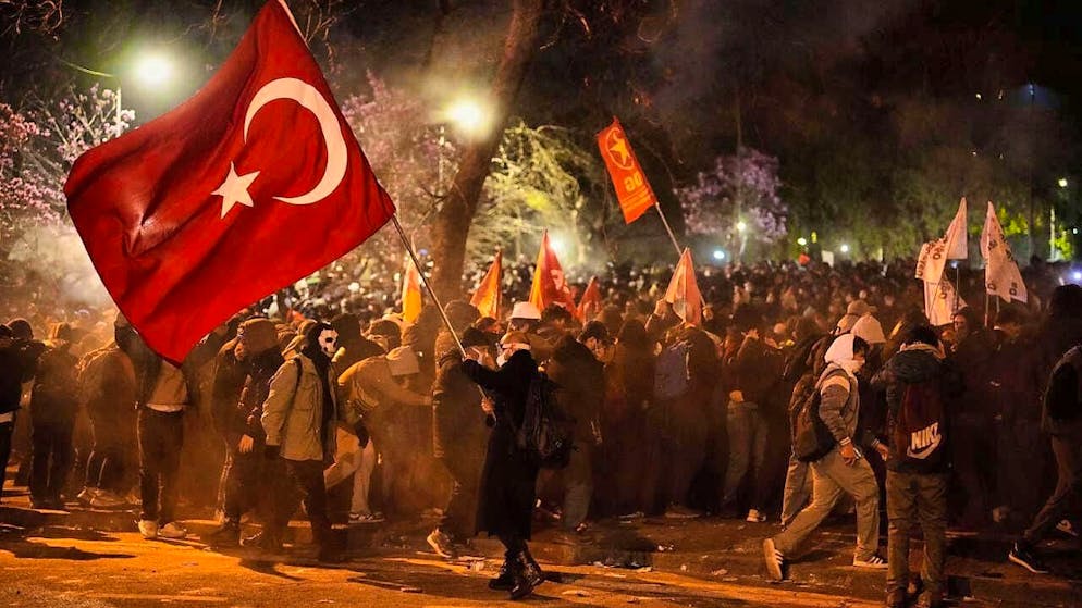 A man holds a Turkish flag as people clash with police during a demonstration against the arrest of Istanbul Mayor Ekrem Imamoglu. Photo: Emrah Gurel/AP/dpa