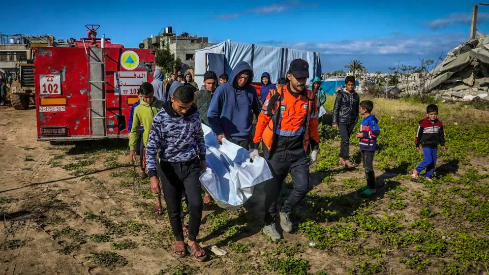 Palestinians carry a body recovered by civil defense workers from under the rubble of a house destroyed by an Israeli airstrike. Photo: Abed Rahim Khatib/dpa