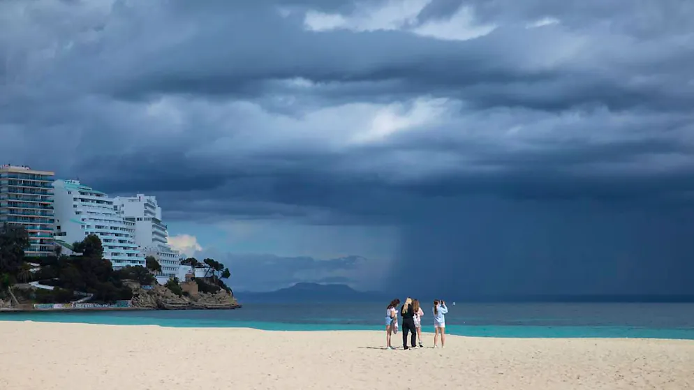 ARCHIV - Menschen spazieren am Strand an einem bewölkten Tag in Magaluf. Foto: Clara Margais/dpa