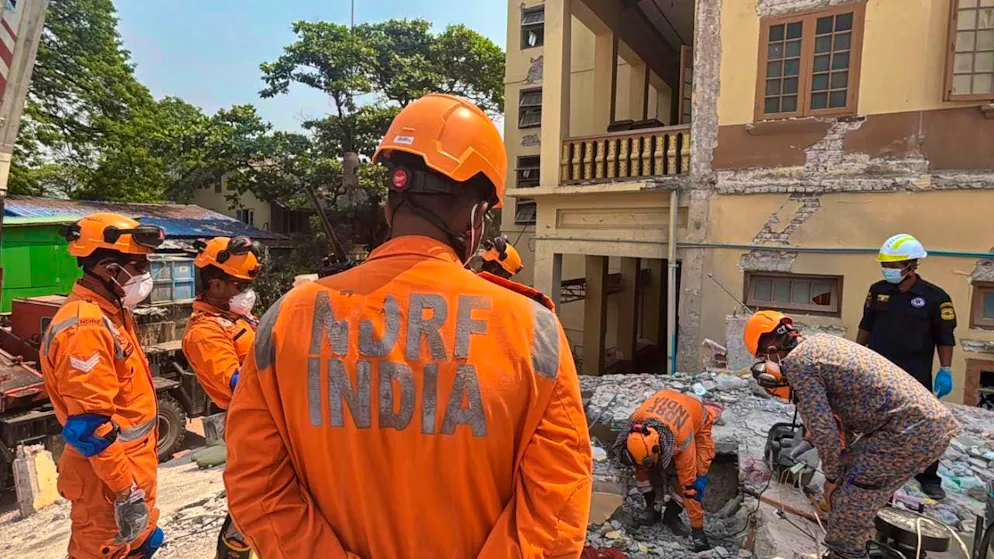 Indian and Myanmarese rescue workers try to carry a body out of the Buddhist monastery U Hla Thein, which collapsed in the earthquake. Photo: Thein Zaw/AP/dpa