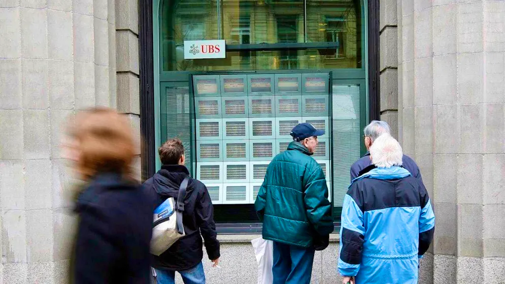 Passers-by in front of screens showing the current stock market prices on Zurich's Bahnhofstrasse. (archive picture)