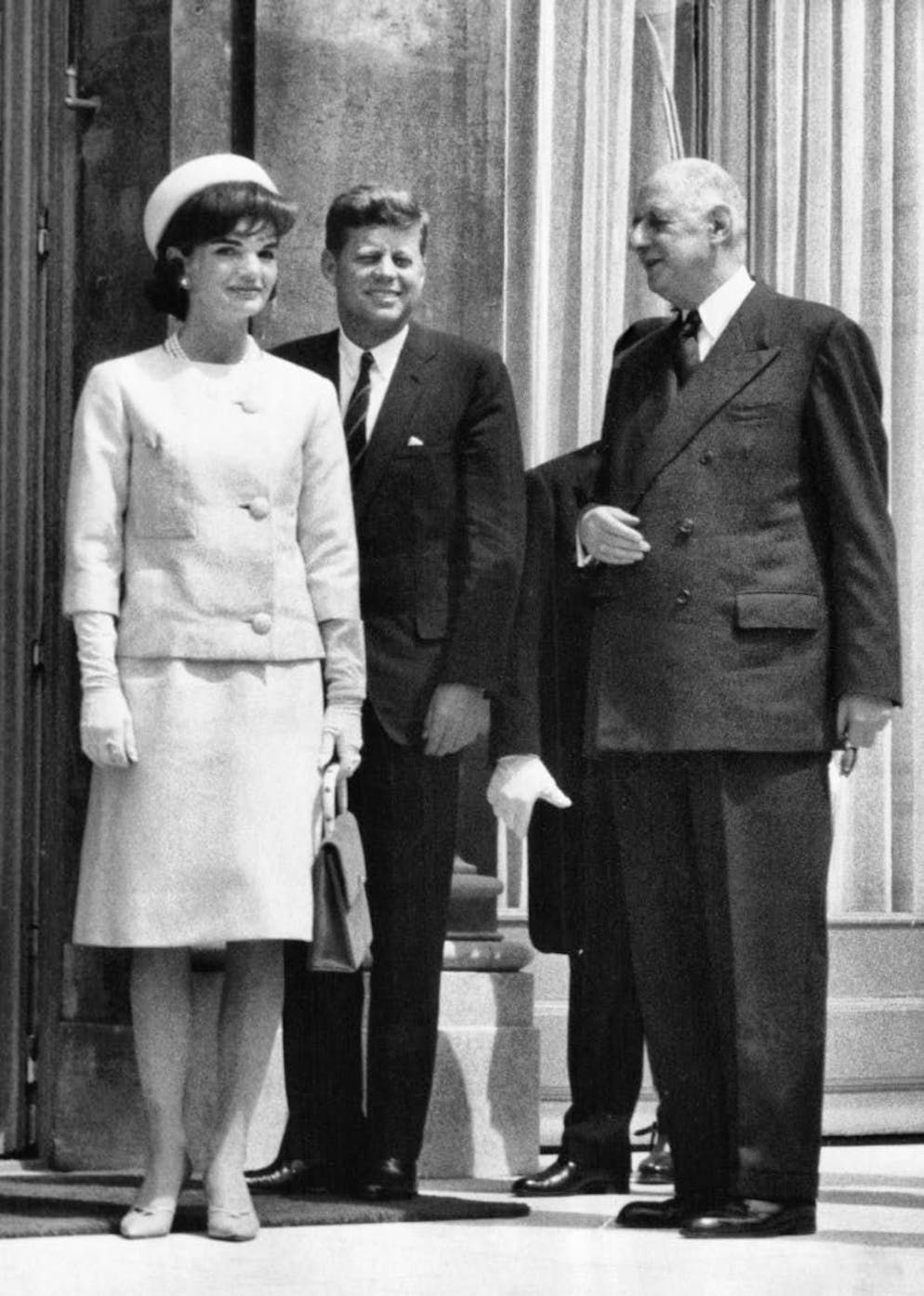 Le celebrità si ispirano all'icona di stile Jackie Kennedy. In occasione di una visita ufficiale in Francia, il 31 maggio 1961, Jacqueline optò per un capospalla del suo guardaroba: un abito con maniche a tre quarti che rivelava guanti lunghi e un cappello a tamburello. Naturalmente la collana di perle era d'obbligo. Nella foto la First Lady con John F. Kennedy e il presidente francese Charles de Gaulle durante un pranzo all'Eliseo.