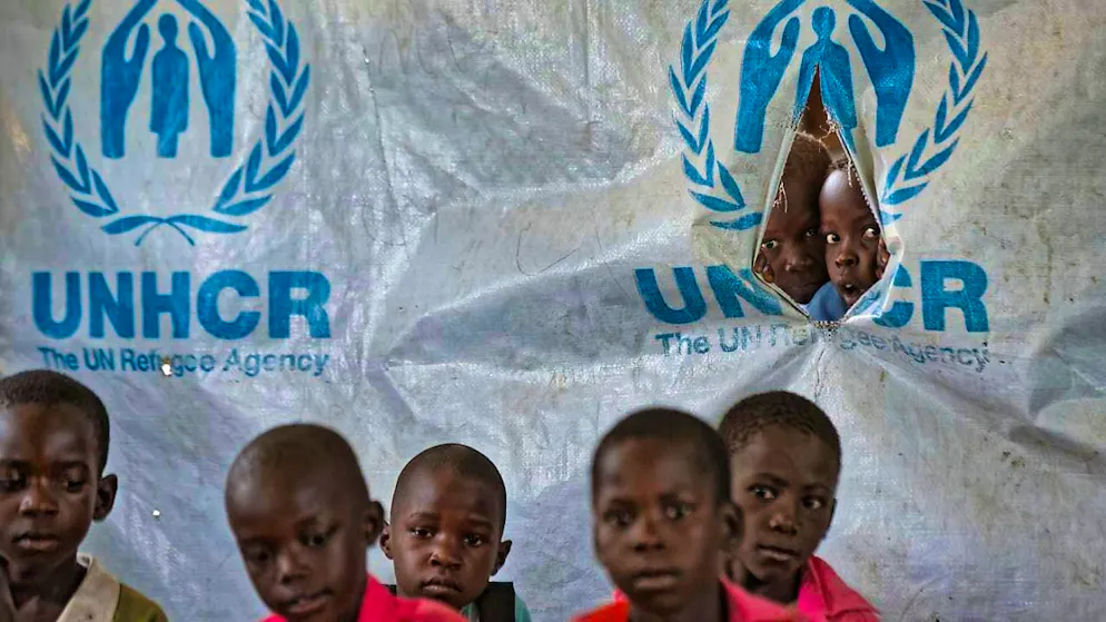 ARCHIVE - Children look through a hole in a UNHCR tent at Ombechi Primary School in the Bidi Bidi refugee camp. Photo: Ben Curtis/AP/dpa