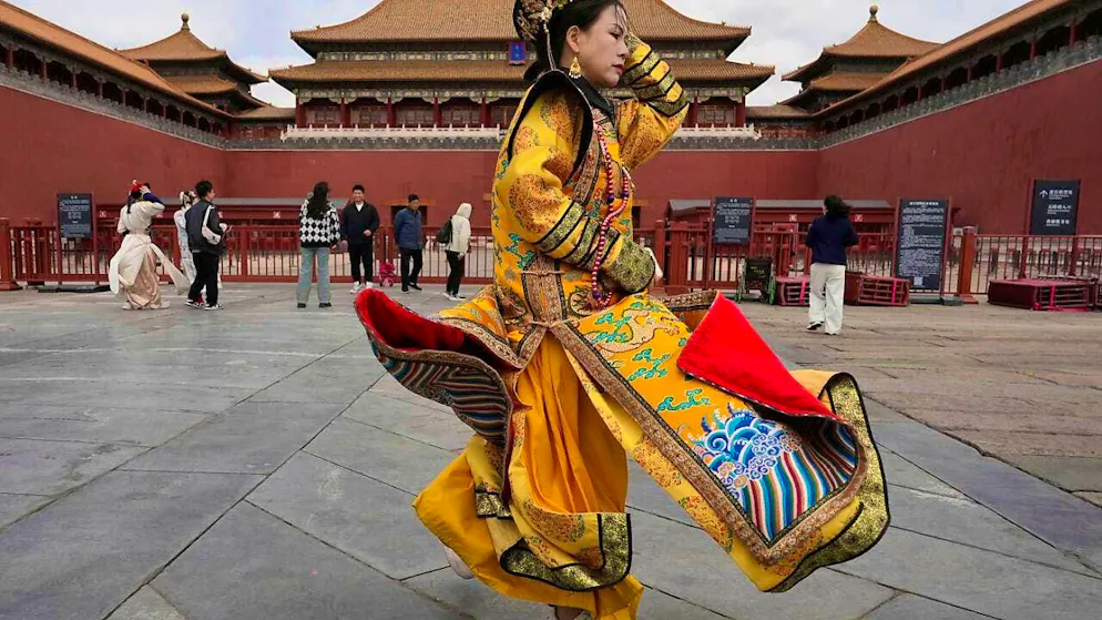 A woman dressed as an empress dowager protects her outfit from the strong wind outside the Forbidden City, which was closed due to storm warnings. Photo: Ng Han Guan/AP/dpa