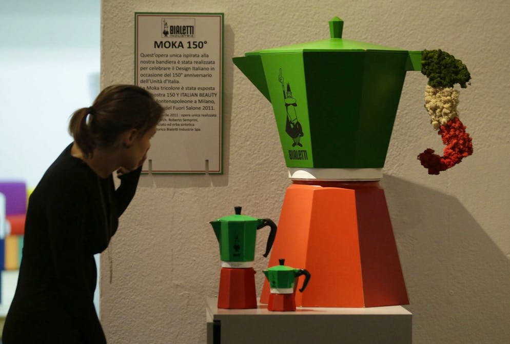 Una donna osserva da vicino la «Moka tricolore» nei colori della bandiera italiana e in diverse dimensioni, esposta alla mostra che celebra l'80° anniversario della popolare caffettiera italiana a Milano, durante un'anteprima per i media, mercoledì 27 novembre 2013. Nel 1933 Alfonso Bialetti progettò la Moka Express, la prima caffettiera della linea dalla particolare forma ottagonale che non è cambiata molto nel corso degli anni.