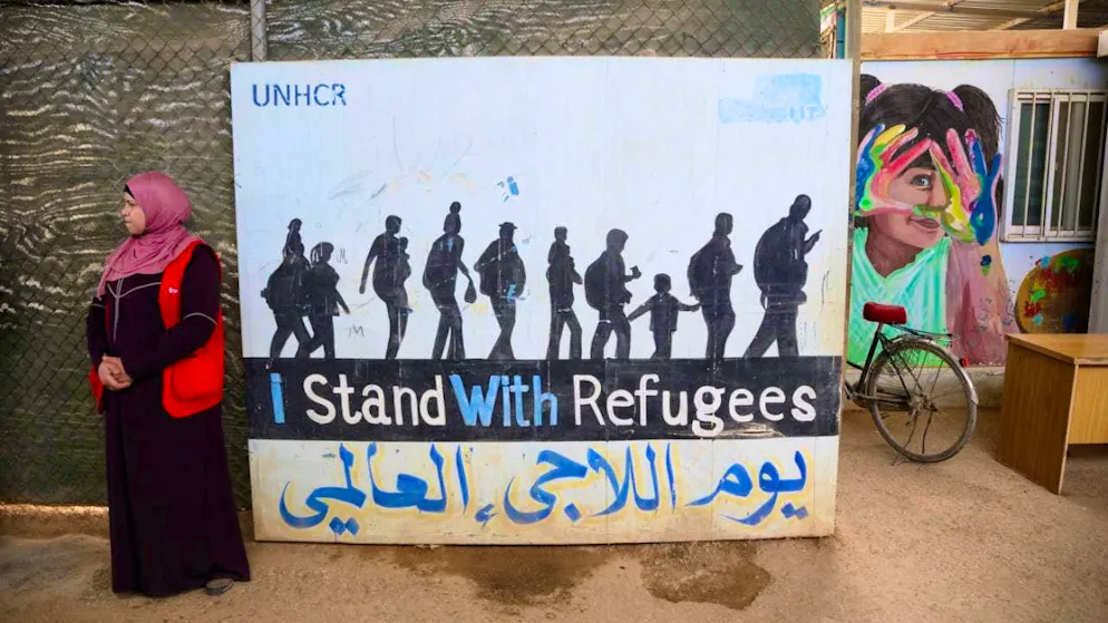 ARCHIVE - A woman stands in front of a poster reading "I stand with Refugees" in the Jordanian refugee camp Saatari. Photo: Bernd von Jutrczenka/dpa